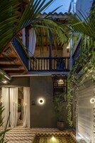 Un patio con piso estampado, una planta en maceta y un balcón con barandilla.