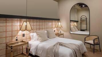 A neatly arranged bedroom with a bed, bedside tables, a chair, and a large mirror.