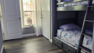 Een slaapkamer met een stapelbed, een ladder, een raam met uitzicht en blauwe LED-verlichting langs het plafond.