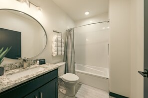 A bathroom with a marble sink, a toilet, a bathtub, and a shower curtain. - Modern Suite ~ Above Starbucks ~ Fast Wi-fi (Logan)