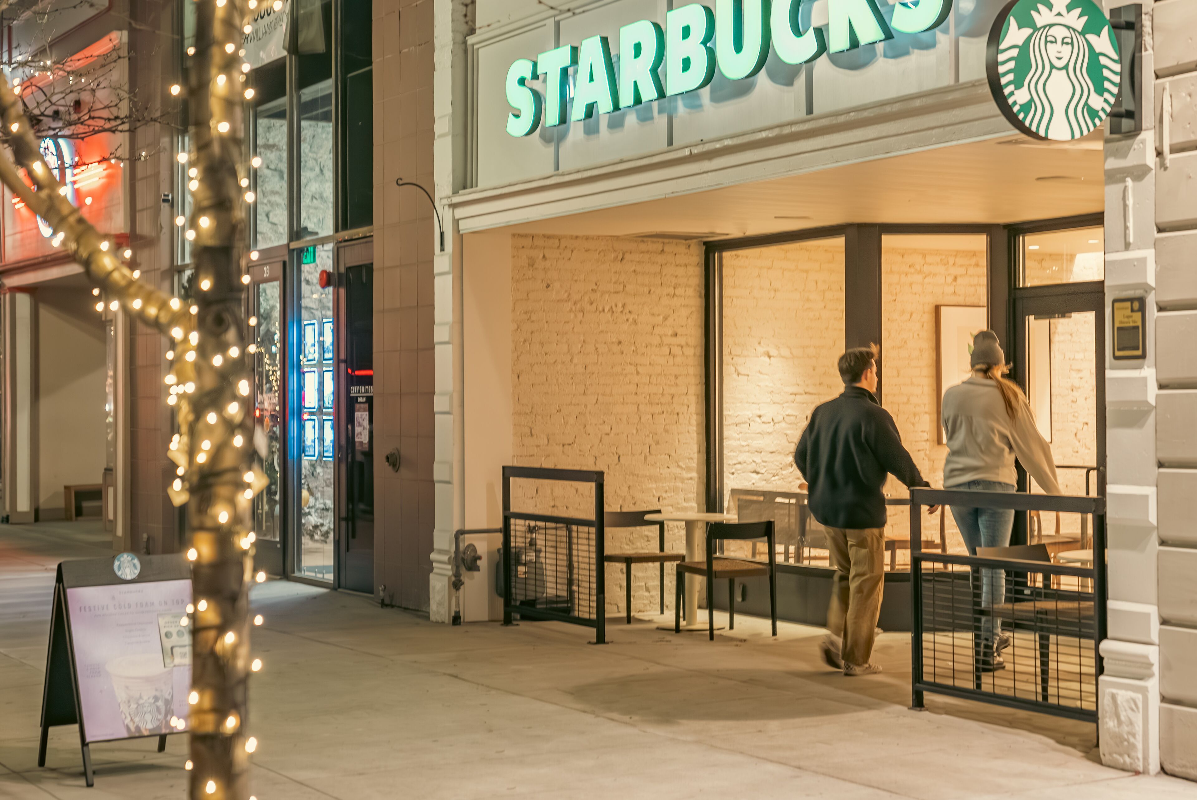 Un établissement Starbucks avec une façade en briques et un espace extérieur aménagé pour les clients.