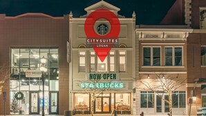Un edificio con un'insegna Starbucks, un'insegna 'APERTURA' e un'insegna 'CITYSUITES LOGAN'.