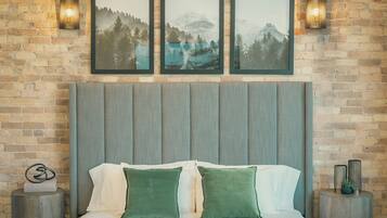 A bedroom with a brick wall, a wooden headboard, and three framed pictures.