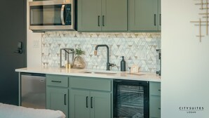 A compact kitchen with a microwave, dishwasher, and a sink with a modern faucet. - Luxury Suite ~ Above Starbucks ~ Main St View (Logan)