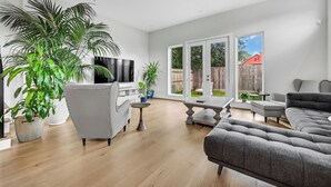 Un salon spacieux doté d’un grand téléviseur, de nombreux sièges et de grandes fenêtres donnant sur le jardin.