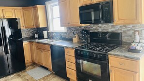 A modern kitchen with wooden cabinets, a black refrigerator, a microwave, a stove, and a dishwasher.