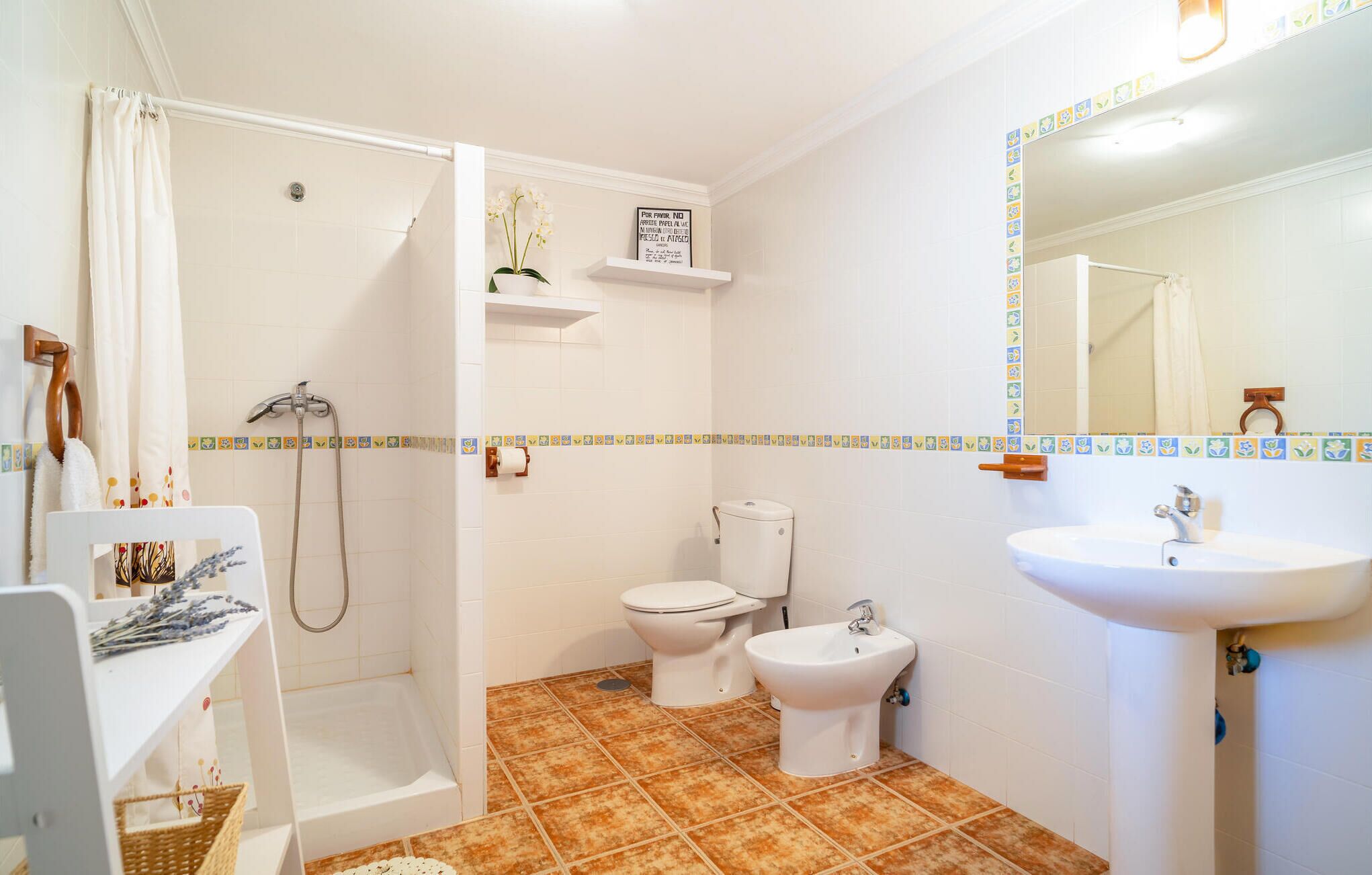 A bathroom with a shower, toilet, bidet, and sink.