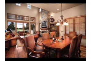 Enjoy meals in this dining area with a large table and comfortable chairs, surrounded by a stone accent wall and a fireplace.