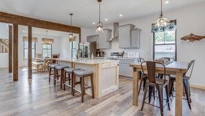 Una cocina moderna con una isla central, taburetes de bar e iluminación colgante.