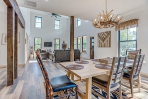 Un vaste espace de vie comprenant une grande table à manger en bois, des sièges confortables et un lustre moderne.