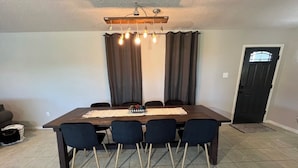 Un coin repas avec une table en bois foncé, six chaises, un set de table en fibres tressées et un luminaire suspendu au-dessus.