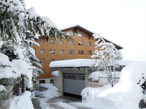 Set amidst snow-covered trees, this hotel features a traditional facade with multiple windows and a convenient garage door.