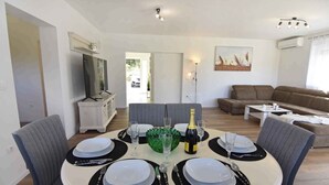 Un coin repas avec une table ronde dressée pour quatre personnes, une bouteille de champagne et un tableau accroché au mur.