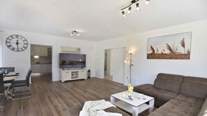 Un salon moderne avec un canapé, une table basse, un téléviseur et une horloge au mur.