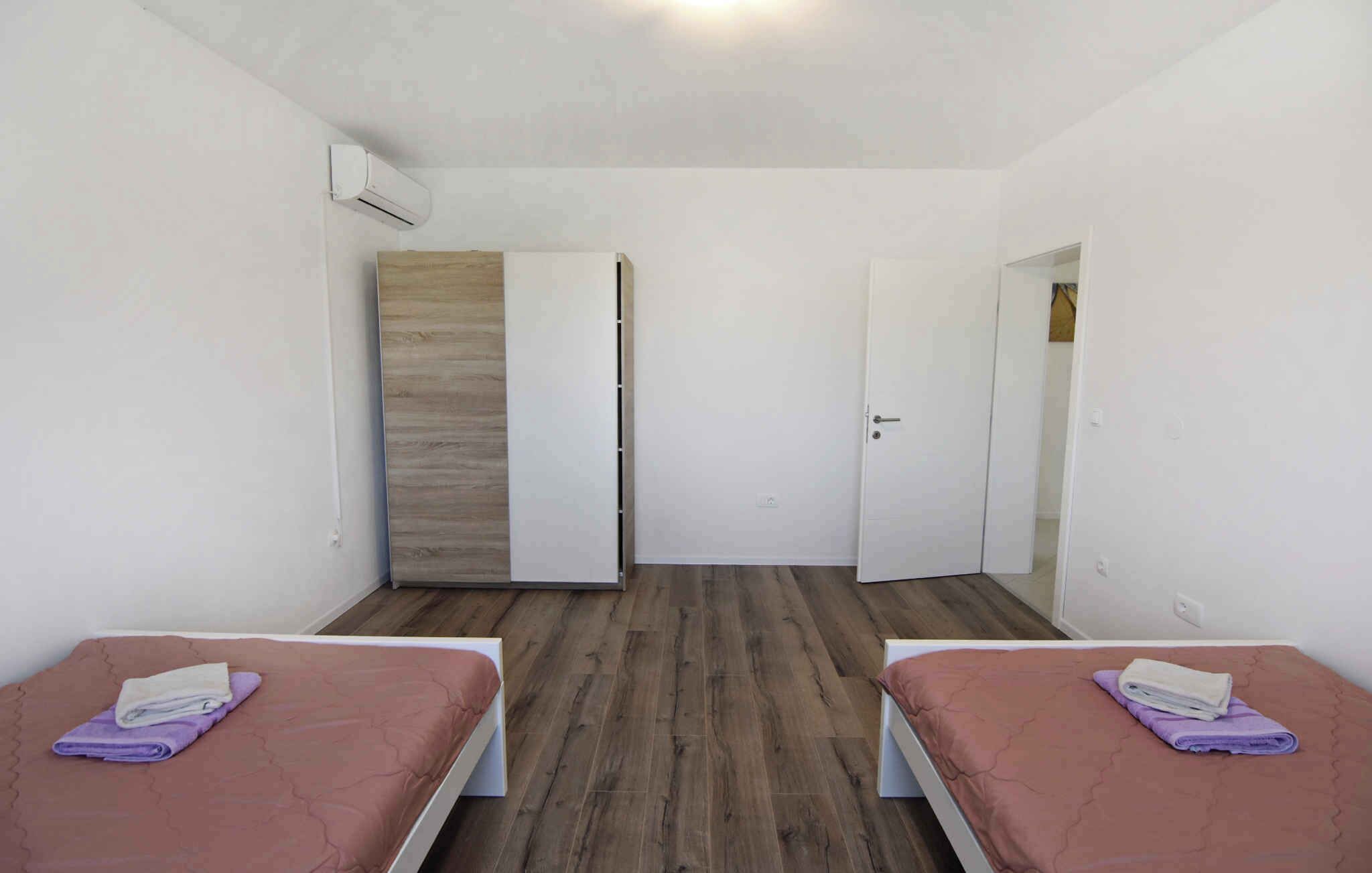 A room with two beds, a wardrobe, and a door.