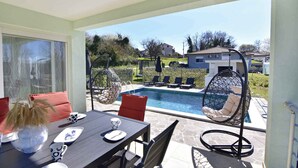 Une terrasse avec piscine, des sièges extérieurs et une vue sur le quartier.
