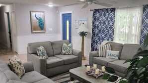 A living room with grey sofas, a coffee table, and a ceiling fan. - Thumb Point Oasis w/Heated Pool- walk to beach! (Fort Pierce)