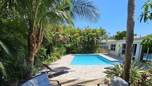 A backyard with a pool, outdoor seating, and lush greenery. - Thumb Point Oasis w/Heated Pool- walk to beach! (Fort Pierce)