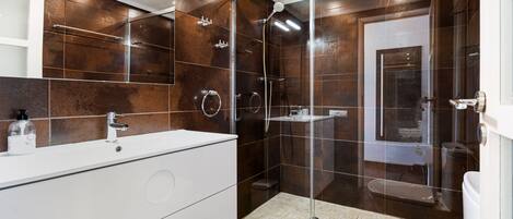 A modern bathroom with a glass-enclosed shower, a white vanity, and a large mirror.