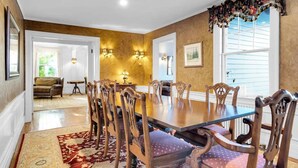Ein Esszimmer mit einem großen Holztisch, verzierten Stühlen und einem gemusterten Teppich.