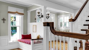 Eine prächtige Treppe mit weißen Balustraden, einer rot gepolsterten Bank und einem Kronleuchter.