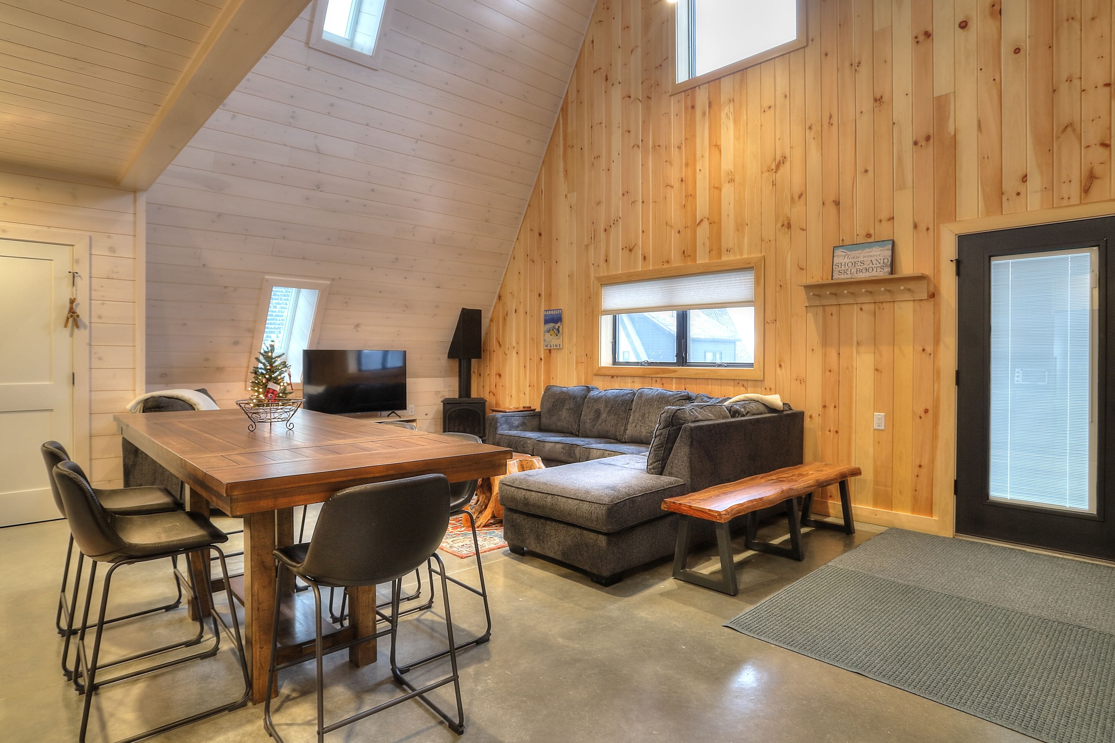 Ein gemütliches Zimmer mit Holzbalkendecke, einem Esstisch mit Stühlen, einer Couch und einer Bank.