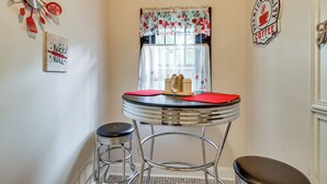 A small kitchen with a round table, two bar stools, a clock, and wall decorations including a coffee sign. - Hike & Bike On-Site: Burgaw Apt - 4 Mi to River (Burgaw)
