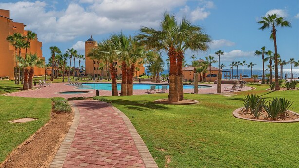 A resort with a central pool, palm trees, and a clear view of the ocean. - Amazing 3BR 2Bath at the Princesa Resort A-505 Ocean View Condo (Puerto Peñasco)