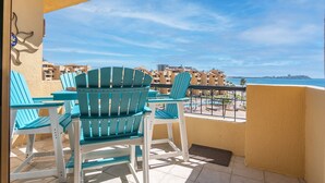 A balcony with turquoise chairs and a view of a coastal area with buildings. - Amazing 3BR 2Bath at the Princesa Resort A-505 Ocean View Condo (Puerto Peñasco)