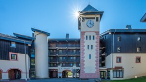 A building with a central clock tower, multiple balconies, and a modern architectural design. - Studio 4 ppl near the ski runs, family friendly (Morillon)