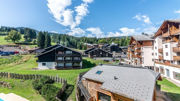 A mountain resort with chalet-style buildings, a wooden fence, and a clear view of the surrounding hills. - Cosy apt 6 ppl near the ski runs with balcony (Morillon)