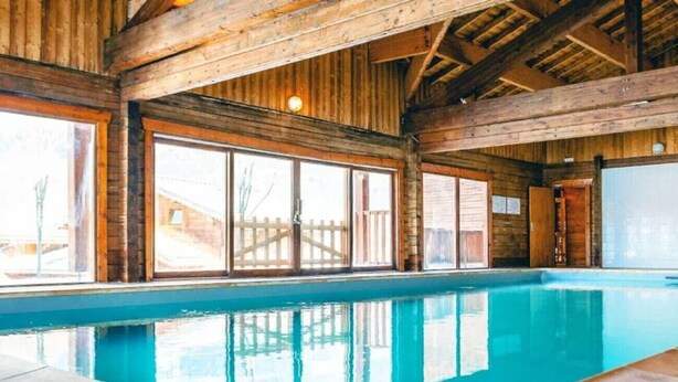 A swimming pool with wooden beams and large windows. - Splendid chalet 8/10 ppl, large terrace, parking (Morillon)