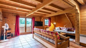 A wooden cabin interior with a sofa, a television, a fan, and a staircase. - Splendid chalet 8/10 ppl, large terrace, parking (Morillon)
