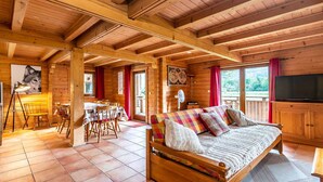 A wooden cabin interior with a dining area, a sofa, and a television. - Splendid chalet 8/10 ppl, large terrace, parking (Morillon)