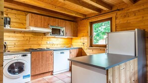 A compact kitchen with wooden walls, a washing machine, a microwave, and a refrigerator. - Splendid chalet 8/10 ppl, large terrace, parking (Morillon)
