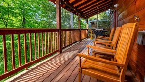 Eine Holzterrasse mit Geländer, Holzstühlen und einem Grill.