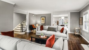 Un salon moderne avec un canapé gris, une table basse et un escalier.