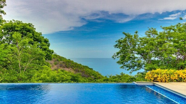 A swimming pool with a view of the sea and lush greenery. - Ocean View 4 Bedroom Villa Steps to Beach & Resort Amenities (Guanacaste Province)