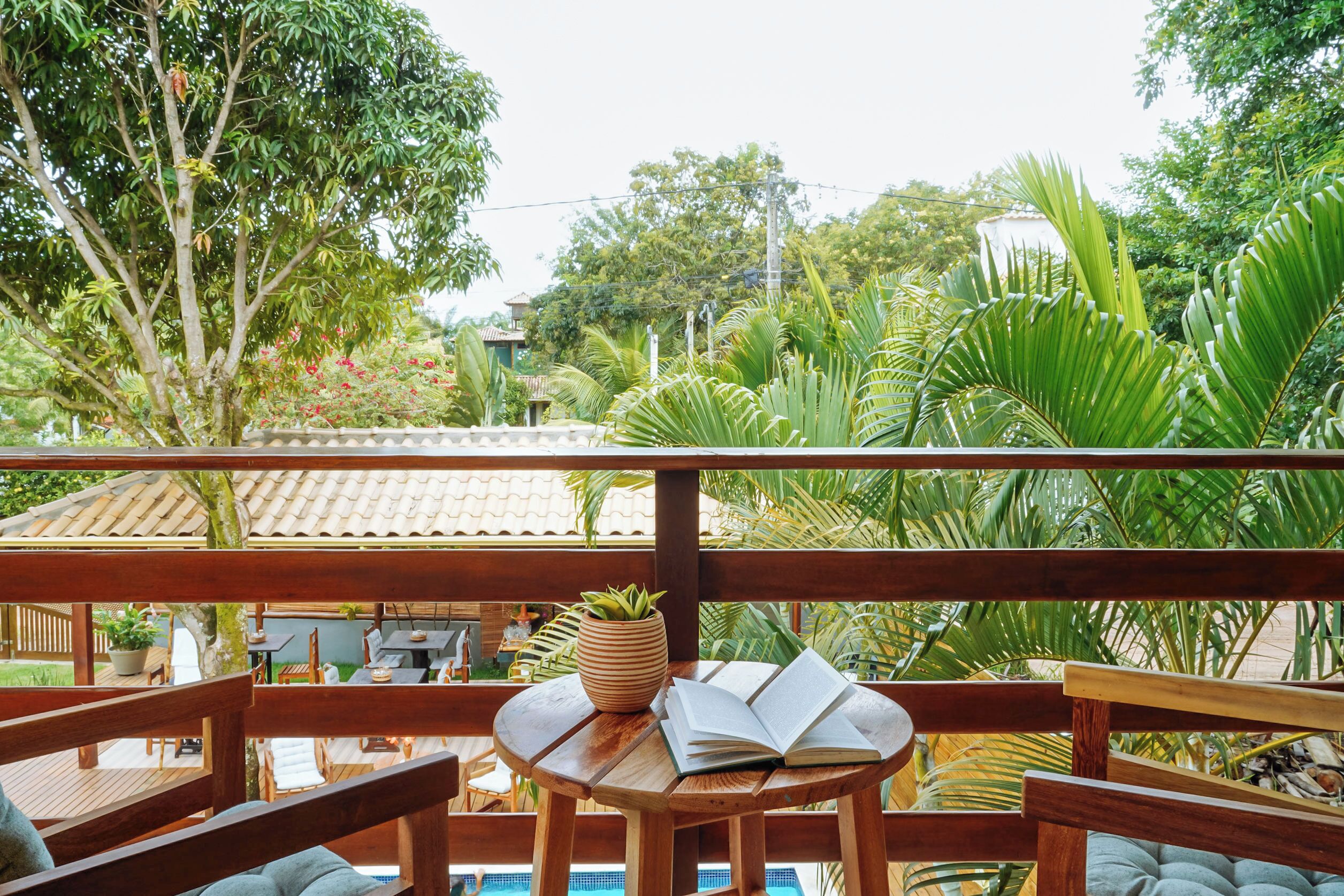 A wooden deck with a table, chairs, and a potted plant.