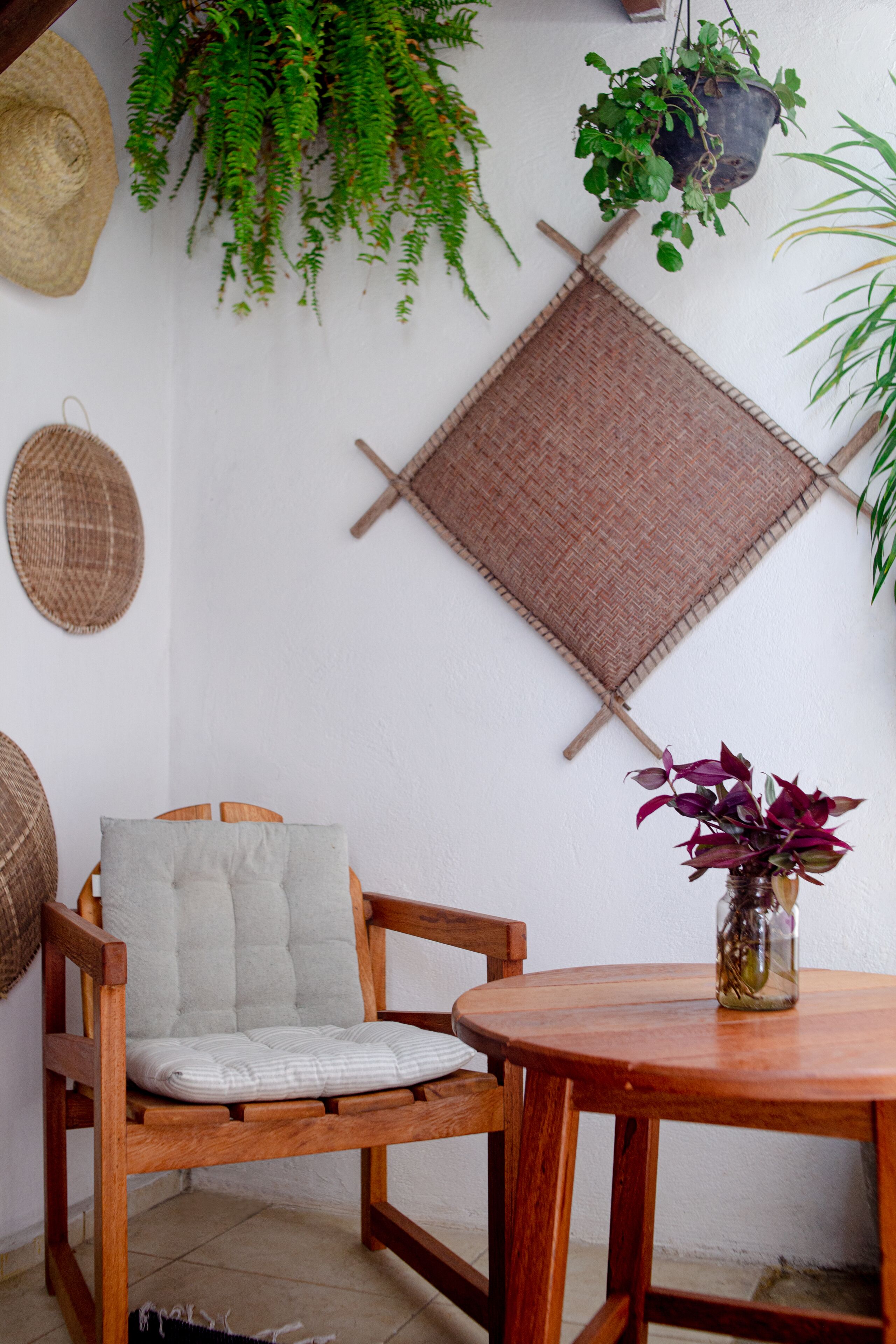 A wooden chair with a cushion, a round wooden table, and a potted plant on the table.