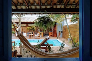 A hammock, wooden deck, pool, and outdoor furniture.