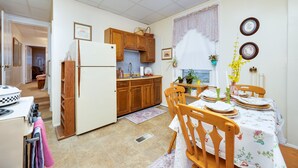 Une cuisine compacte dotée de meubles en bois, d’un réfrigérateur et d’un coin repas avec une table dressée pour deux personnes.