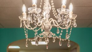 Un lustre à plusieurs lampes, orné de décorations en cristal, dans une pièce aux murs de couleur turquoise.