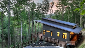 Eine moderne Holzhütte mit einer Terrasse, umgeben von einem Wald.