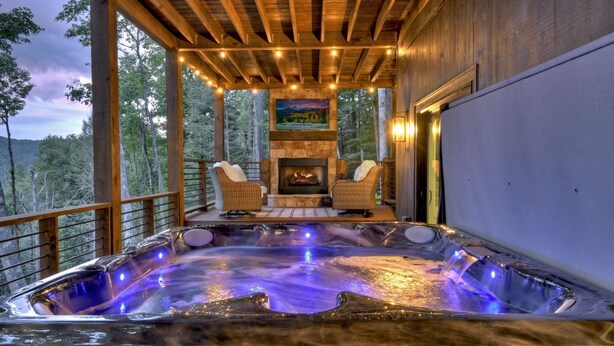 Ein Whirlpool mit Holzterrasse und Stühlen, umgeben von Blick ins Waldgebiet.