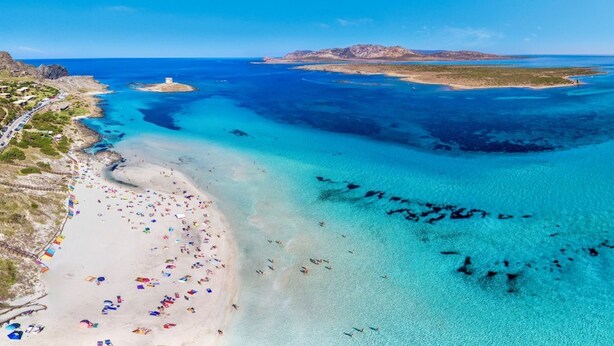 An aerial view of a beach with clear turquoise waters, a sandy shore, and a small island in the distance. - 60 sq m - Living room with kitchenette and double sofa bed, double bedroom, bathroom with bidet and showeror bathtub.<br>Ground floor with furnished veranda.<br>Equipped with:<br>- tv <br>- washing machine<br>- 1 beach umbrella<br>- iron and ironing boar (Stintino)
