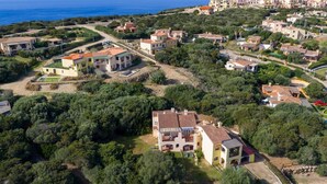 An aerial view of a coastal residential area with houses, greenery, and a clear view of the sea. - 60 sq m - Living room with kitchenette and double sofa bed, double bedroom, bathroom with bidet and showeror bathtub.<br>Ground floor with furnished veranda.<br>Equipped with:<br>- tv <br>- washing machine<br>- 1 beach umbrella<br>- iron and ironing boar (Stintino)