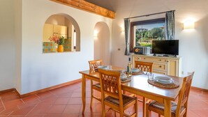 A dining area with a wooden table, chairs, and a television on a cabinet. - 60 sq m - Living room with kitchenette and double sofa bed, double bedroom, bathroom with bidet and shower or bath, access to communal pool. <br>Ground floor or first floor with furnished veranda or balcony.<br>Equipped with:<br>- tv <br>- washing machin (Stintino)