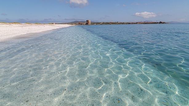 A clear beach with a sandy shore and calm waters.