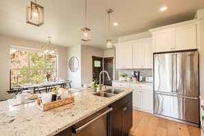 A modern kitchen with a granite countertop, stainless steel appliances, and pendant lighting. - End Unit with Private Hot Tub, Theater Room and Ski Resort Views (Kamas)